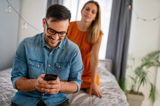 Jealousy woman spying boyfriend and watching his mobile phone. Couple cheating jealousy concept